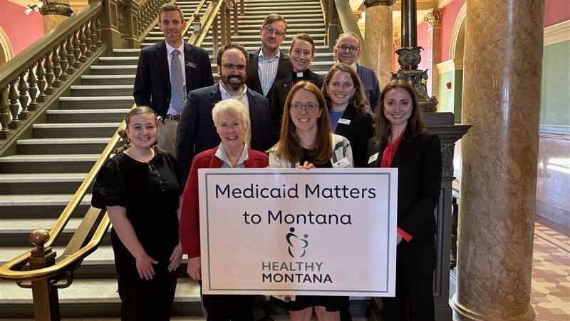 A group of people standing on stair inside the building holding a sign that say Medicaid Matter to Montana