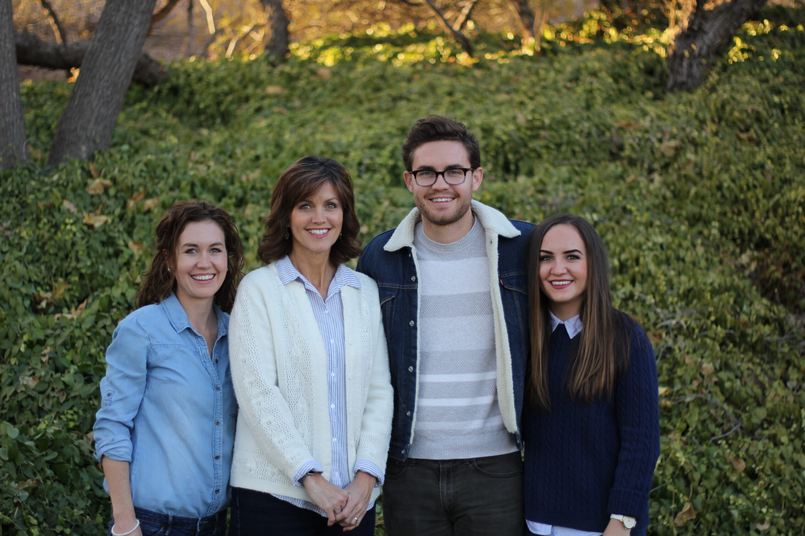 A middle aged worman surrounded by her three adult children. One son and two daughters.