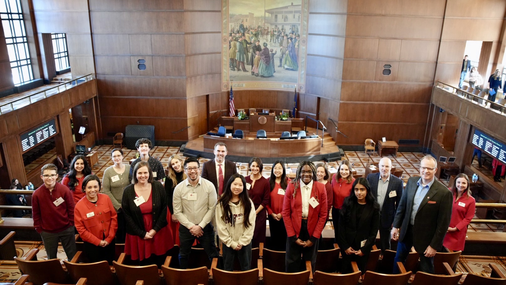 A group of people standing inside the Oregon state capitol senate chamber.
