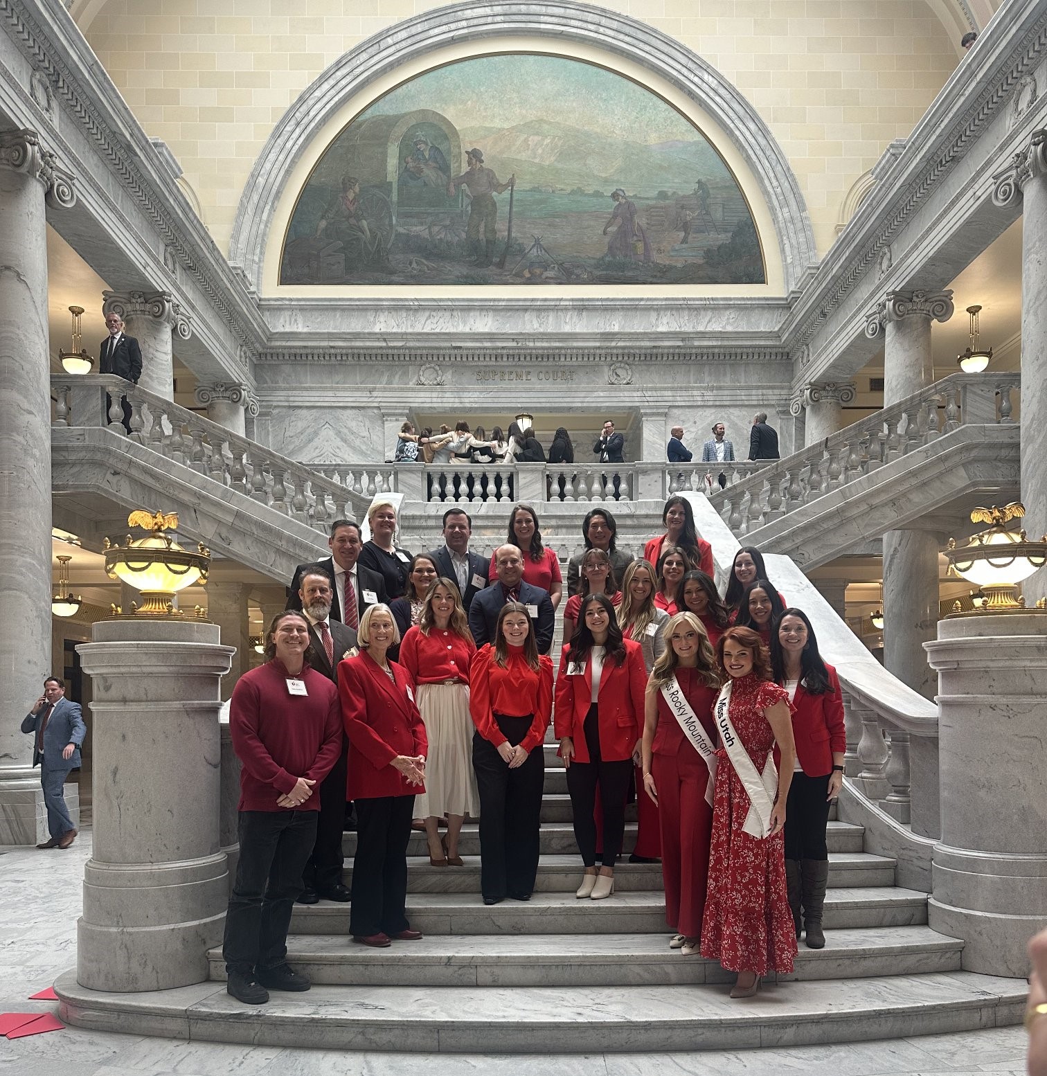A group of people standing on the stairs inside the Utah Capitol building.