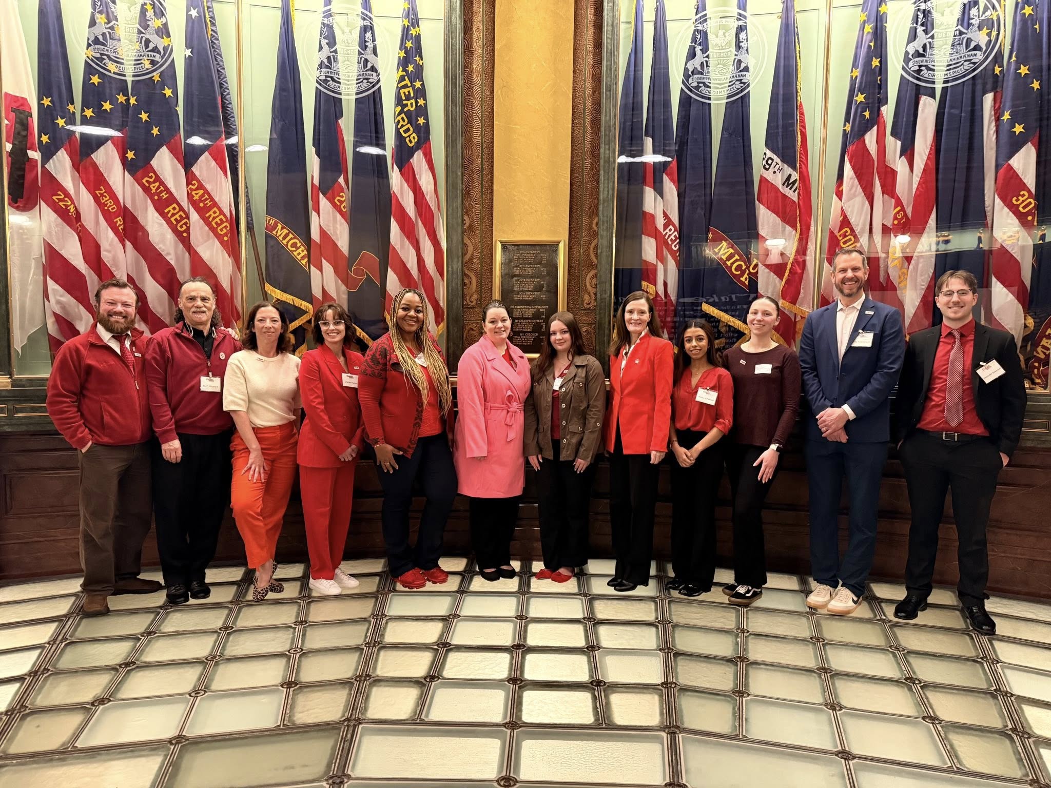 Group of advocates standing infront of a line of flags in the Michigan Capitol rotunda.